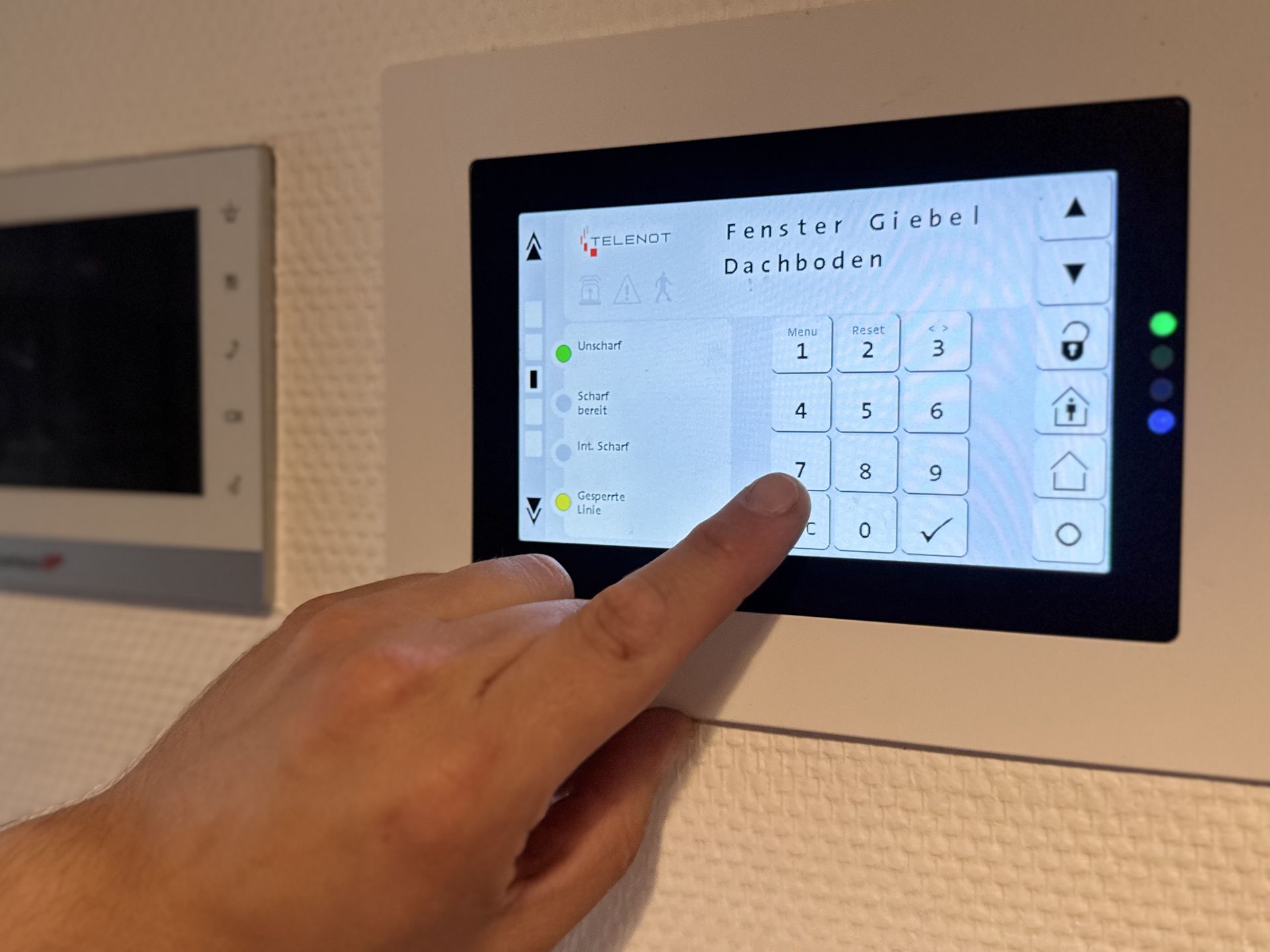 Hand tippt auf Nummerntastatur eines Telenot-Bedienfelds mit den Beschriftungen 'Fenster Giebel Dachboden'